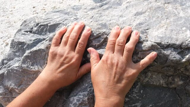 Hand of senior woman climbs a rock and slides down, the concept of hopelessness, failure and tiredness and problems of the elderly