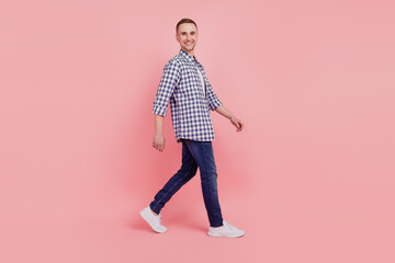 Full length profile side portrait of young handsome guy go walk step happy positive smile isolated over pink background