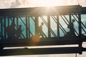 Silhouettes of people walking at busy airport. Passengers walking inside boarding bridge. .