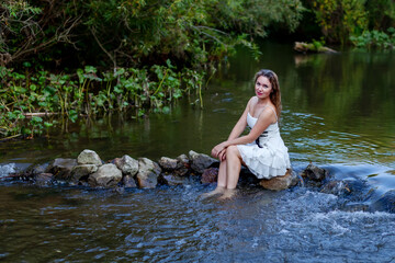 woman in white dress splashes in the river