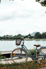 A bicycle with a basket stands on the shore of the lake Annecy at the pier
