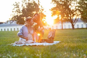 Beautiful pregnant couple having a picnic at sunset