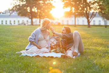 Beautiful pregnant couple having a picnic at sunset