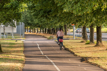 A lonely cyclist riding down a bike path in low sunset light.