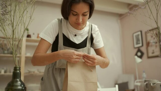 Craftswoman wrapping clay item into paper bag