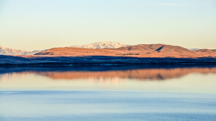 A mountain range reflected on a calm, blue lake on a fresh, clear day