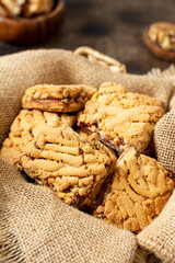 Shortbread cookies with cherry jam in a basket on the brown kitchen table. Delicious homemade sweet pastries	