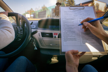 Examiner filling in driver's license road test form - obrazy, fototapety, plakaty