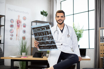 Medicine, radiology and healthcare concept. Happy smiling male indian doctor white coat, holding...