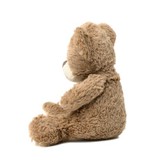 cute brown teddy bear sitting sideways on white isolated background