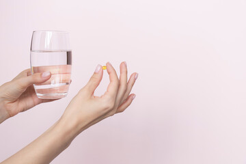 Woman holding pill and glass of water in hands taking emergency medicine, supplements or antibiotic antidepressant painkiller medication to relieve pain, meds side effects concept, close up view
