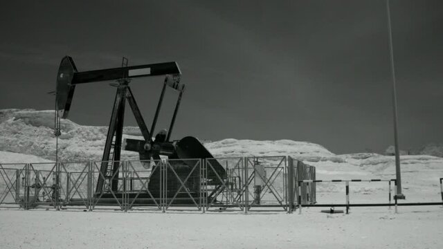 Panning shot of oil pump working in desert, shot in infrared