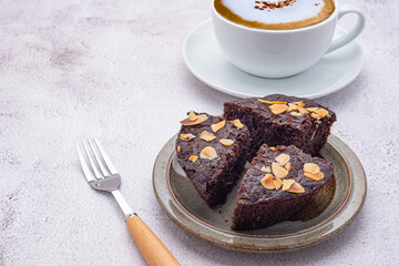 Pieces of fresh brownies on a plate and a white coffee cup. Side view. Delicious chocolate pie....