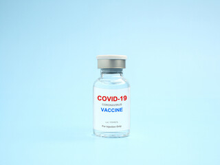 COVID-19 vaccine in a glass bottle on a light blue background. Vaccine for immunization, and treatment from coronavirus infection. Side view. Close-up photo. Concept of medical and healthcare