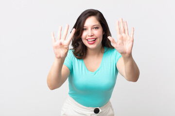 pretty woman smiling and looking friendly, showing number nine or ninth with hand forward, counting...