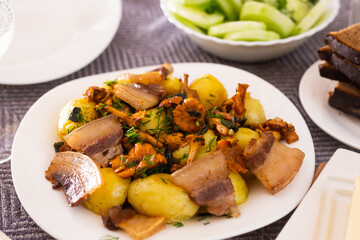 traditional rustic dish. fried potatoes with chanterelle mushrooms and pork brisket with herbs