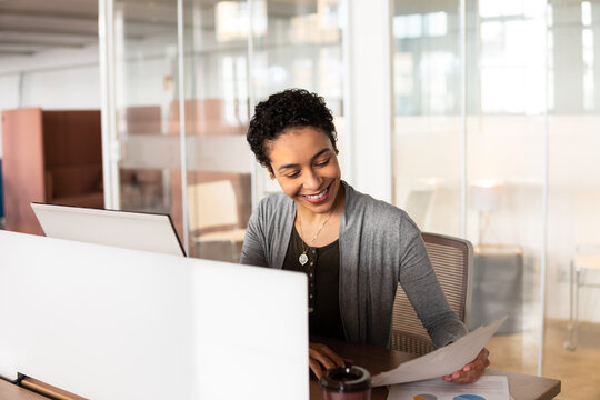 happy mixed race businesswoman analyzing new project and documents in coworking office . - Powered by Adobe
