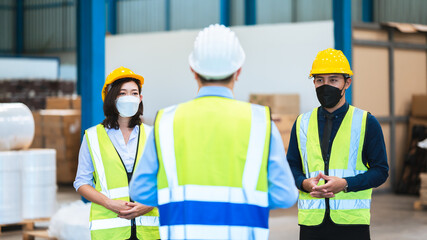 The factory employee consists of engineers, foreman, technicians, and related department staff. Wear a mask, hard hat, and vest. meeting before starting work inside the warehouse. Teamwork concept.