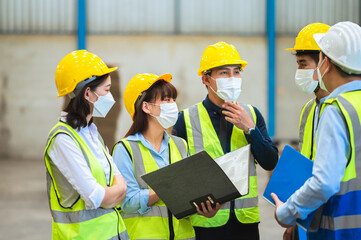 The factory employee consists of engineers, foreman, technicians, and related department staff. Wear a mask, hard hat, and vest. meeting before starting work inside the warehouse. Teamwork concept.