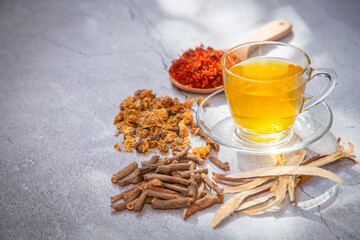 Cup of herbal tea and some dried herb , sufflower, licorice root and Chrysanthemum .