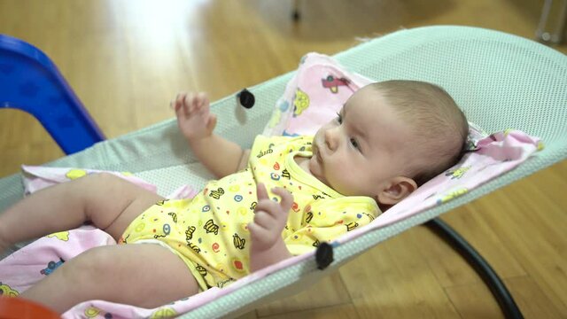 Newborn jerks arms and legs in a baby rocking chair