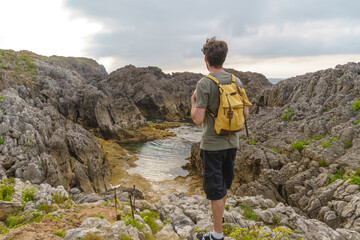 Unrecognizable man hiking in a cliff. Horizontal view of backpacker traveler in mountains and river