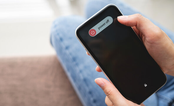 Woman Hand Using Is Sliding To Turn Off The Mobile Phone To Reduce Power Consumption. Technology And Environment Concept