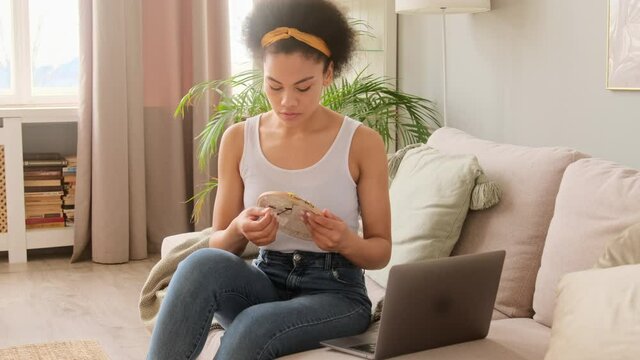 African american woman embroiders with thread and needle a beautiful pattern at home focused and enjoy needlework learning with online tutorial class on laptop. Traditional handicraft hobby.