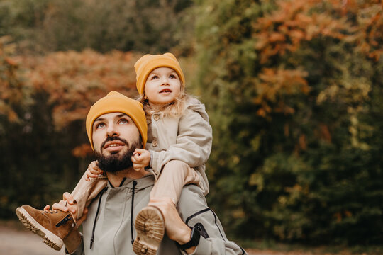 Happy father and daughter playing while walking in a beautiful autumn park. Ideal weekend father with his little daughter, autumnal mood