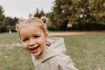 portrait of a little cute girl who smiles and looks straight into the camera when walking in the autumn park