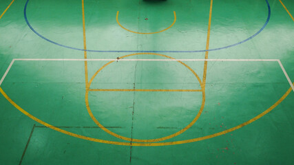 Green basketball court seen from above, with various marks of time, its markings are dirty and discolored