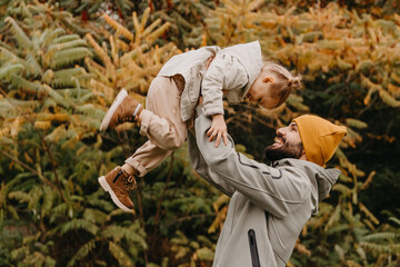Happy father and daughter playing while walking in a beautiful autumn park. Ideal weekend father...