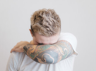 Portrait of a modern young guy with a tattoo on his arm. The man covers himself from the camera...