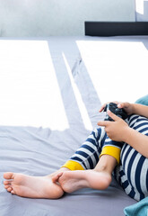 Boy holding joystick gaming controller in hands, playing video game at home.