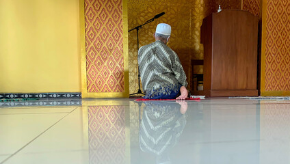 An old man wearing Batik praying in a mosque in Yogyakarta, Indonesia