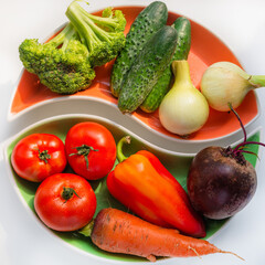 Sets of red and green vegetables on multi-colored plates in the form of a symbol - harmony. Flat lay