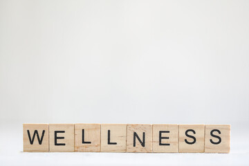 WELLNESS text in wooden block letters on plain white background with copy space