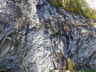 View from the water on the steep slope of the flooded Marble Canyon in the Ruskeala Mountain Park on a sunny summer day.