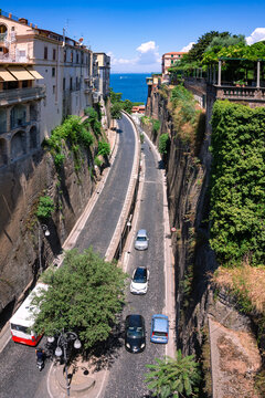 A view from downtown Sorrento, Italy from the bridge of the Tasso marketplace to the Gulf of Naples. A narrow road winds through the valley between rocks built with houses.