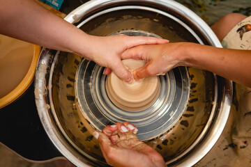 Potter working on potters wheel with clay. Process of making ceramic tableware in pottery workshop....
