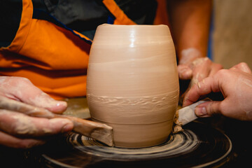 Fototapeta na wymiar Potter working on potters wheel with clay. Process of making ceramic tableware in pottery workshop. Handicraft and art concept.