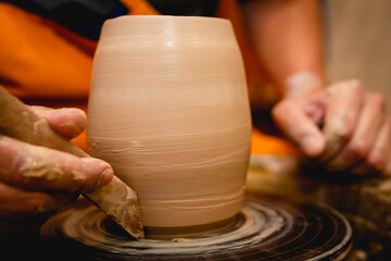 Potter working on potters wheel with clay. Process of making ceramic tableware in pottery workshop. Handicraft and art concept.