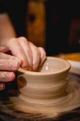 Potter working on potters wheel with clay. Process of making ceramic tableware in pottery workshop. Handicraft and art concept.