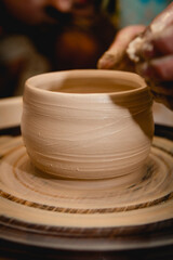 Potter working on potters wheel with clay. Process of making ceramic tableware in pottery workshop. Handicraft and art concept.