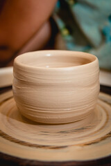 Potter working on potters wheel with clay. Process of making ceramic tableware in pottery workshop. Handicraft and art concept.