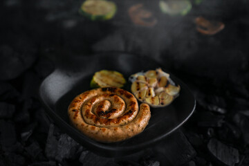 Close-up spiral charcoal sausages cooked in a cast iron pan