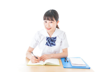 机で勉強をする制服姿の女子学生