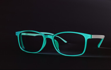 Fototapeta na wymiar Modern eyeglasses in blue color on black background. Casual eye accessory design in futuristic mood.