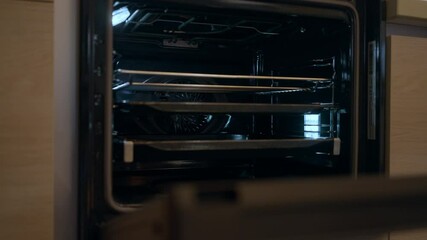 Door of oven opening showing inside of brand new household appliance in shop. Close-up of gas oven indoors in kitchen appliances store. Selling and buying