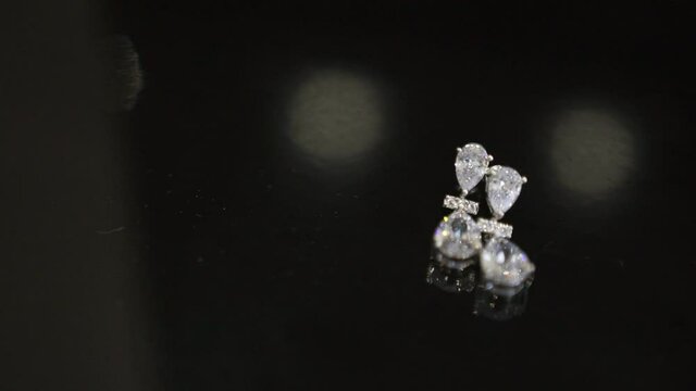Exquisite jewelry - earrings with diamonds lie on a black table. Jewelry for women. Expensive luxury earrings